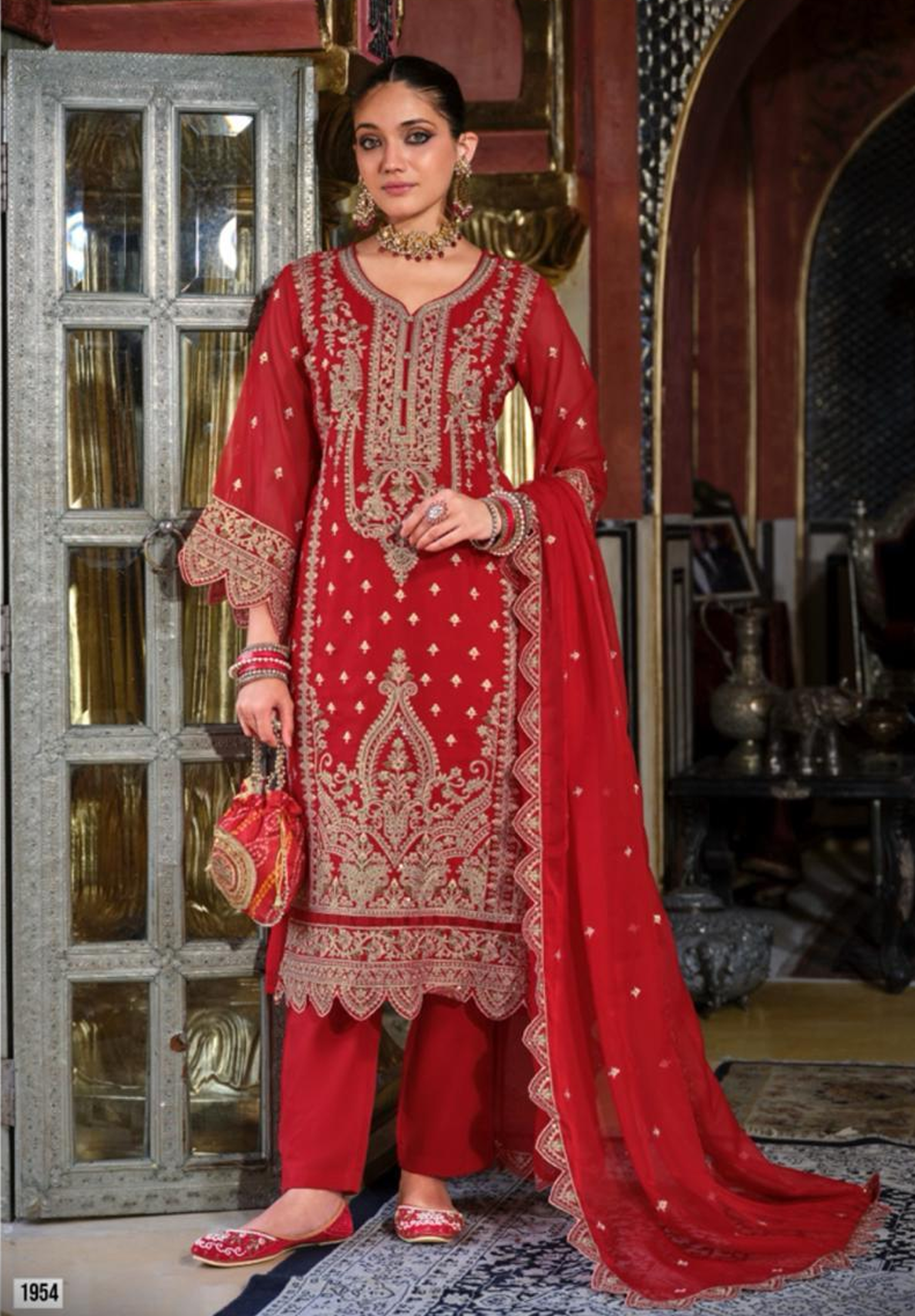Woman in a red embroidered traditional outfit standing in an ornate interior setting.