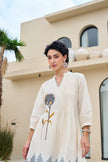 Woman wearing a white dress with floral embroidery outdoors